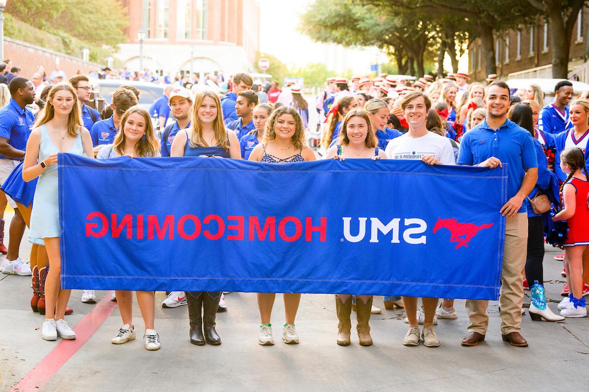 People holding up a large banner that reads SMU homecoming